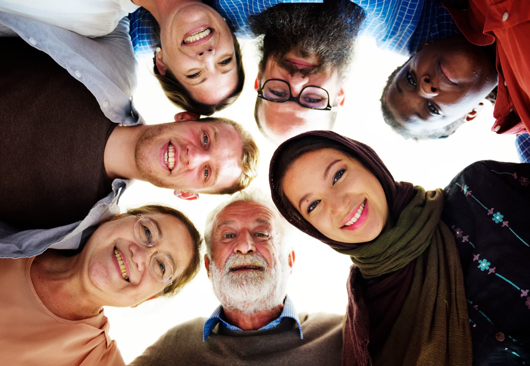 A circle of smiling people of different ages looking down at the camera